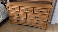 Front view of honey-brown oak dresser, seven drawers, brushed nickel pulls