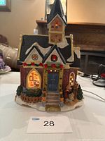 Front view of illuminated ceramic church with snow roof and nativity scene