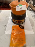 Full view of Lyman Turbo 600 tumbler on table with guide book