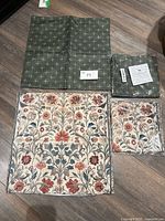 All four pillow sham covers displayed: one green unfolded, one green folded in packaging, one floral unfolded, one floral in packaging