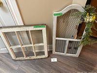 square six-pane glass window frame and arched decorative window leaning against wall