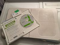 Balance board with open Wii Fit game case showing disc and insert