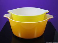 Orange and yellow Pyrex bowls nested together showing exterior colors and handles
