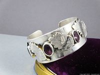 Angled view of silver cuff showing leaf appliqués and amethyst stones