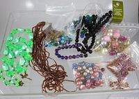 Overview of necklaces and multiple bags of loose beads on tray