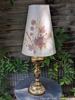 Full view of brass table lamp with floral shade