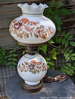 Full view of lamp showing both globes, floral pattern, metal base, cord