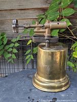 Full view of brass blowtorch front, showing tank, base, burner, control knob