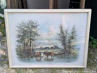Full view of framed pastoral cattle print standing outdoors