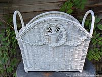 Front view of white wicker magazine rack with handles and sunburst motif
