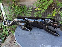 Full left-side view of glossy black ceramic panther figurine on table