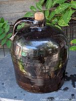 Front view of dark brown stoneware jug with cork showing full form and finish