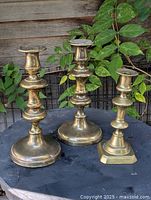 Three brass candlesticks on table