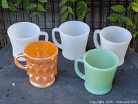 Group shot of five Fire-King mugs: three white, one jadeite, one marigold Kimberly