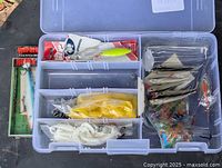 Open Plano tackle box displaying compartments and assorted lures, soft baits, weights