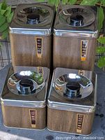 Front view of all four canisters stacked, showing labels and wood-grain finish