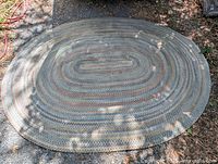 Full view of entire oval braided rug laid flat outdoors