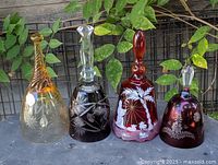 Four decorated glass bells lined up showing overall colors and designs