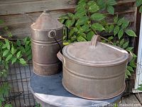 Tin kerosene can and steam cooker together on table