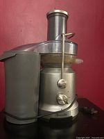 Side view of Breville juicer showing base, lid, chute, pulp bin, cord