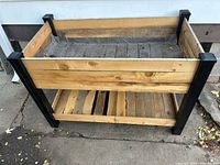 Front view of elevated wooden garden bed showing fabric liner and shelf