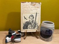 Front view of Gene Hill book on stand beside Ducks Unlimited mug and napkin rings
