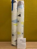 Two rolled wallpaper packages standing upright with pattern visible