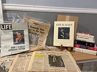 Overall lot showing Life magazine, boxed Four Days book on stand, newspapers, stack of books