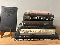 Ten books stacked with Harmony in Dress booklet on stand