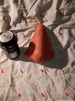 Front view of nose-shaped dispenser beside soda can for scale