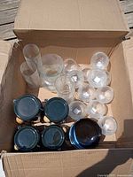 Overall view of all items inside cardboard box: clip-top canisters, tumblers, ribbed bowls
