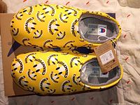 Top view of new Champion yellow slip-on shoes with tags attached, showing size label inside.