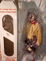 Box front with Ben porcelain clown doll visible inside plastic wrap