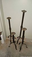 All four wrought iron candlesticks varying heights
