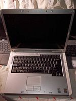 Open Dell Inspiron laptop placed on top of another laptop, showing keyboard and screen