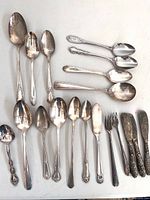 Overview of 21 mixed silverplate flatware pieces on table