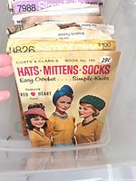 Box with visible Coats & Clark crochet booklet and stacked pattern envelopes behind