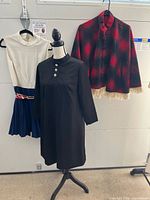 All three garments displayed: black dress on mannequin, plaid poncho, sleeveless dress
