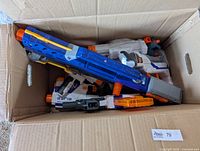Overview of cardboard box showing multiple Nerf blasters piled together