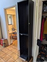 Full view of tall narrow black Ikea bookcase with shelf holes visible