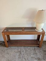 Front view of glass top walnut console table with lamp placed on right side