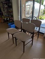 Front three-quarter view showing all four teak and tweed chairs