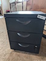 Front view showing three drawers, key in lock, casters visible