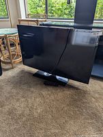 Front view of Toshiba TV on stand with remote on carpet