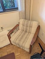 Front angled view of teak and tweed armchair