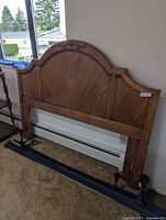 front view of wood queen headboard with metal frame rails placed below