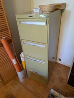 Full view of olive green 4-drawer cabinet with surrounding items
