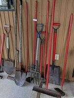 Full group of long-handled tools leaning against wall