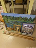 Tripod disassembled with three artworks leaning against wall