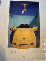 front of poster showing yellow 1986 Corvette and Get Vette caption